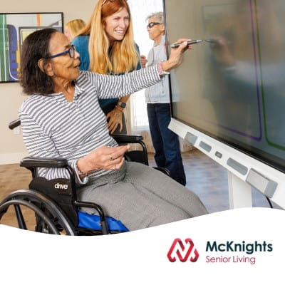 A senior resident with her caregiver, interacting on a SMART Board using digital ink.