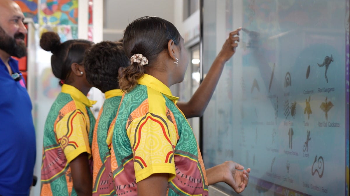 Three students interacting with a SMART interactive display to communicate their story, in ways that Aboriginal people do.