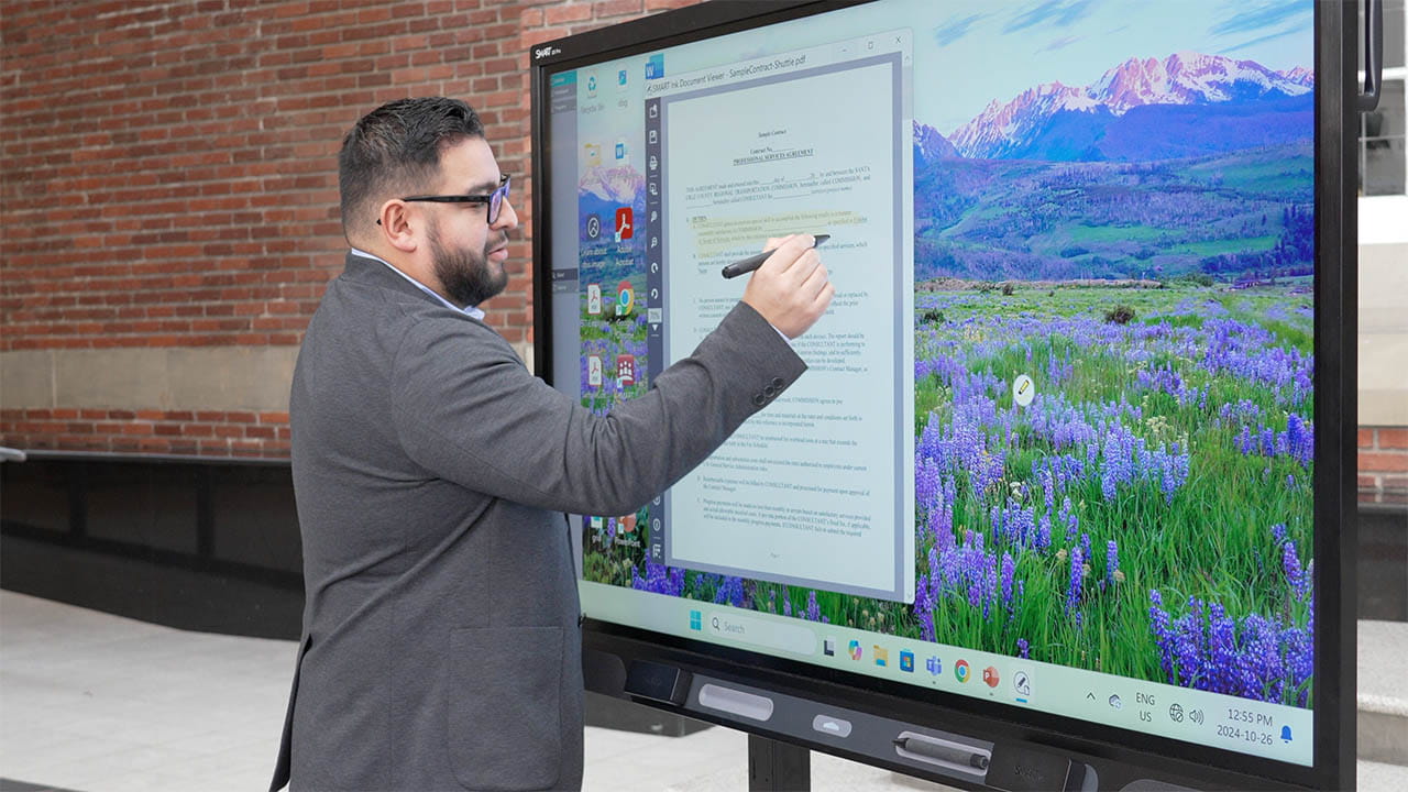 Business professional reviewing and annotating a document on a SMART Board with a digital pen.
