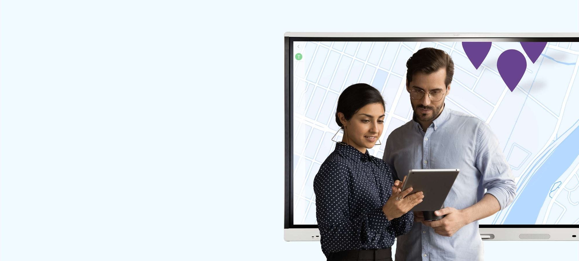 Two colleagues collaborating with a tablet using SMART technology for remote management, with an interactive SMART Board in the background.