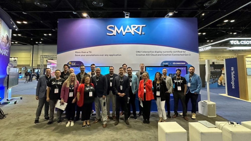 SMART Technologies team posing together at the ISE event in front of their exhibition booth, which highlights their interactive display solutions.