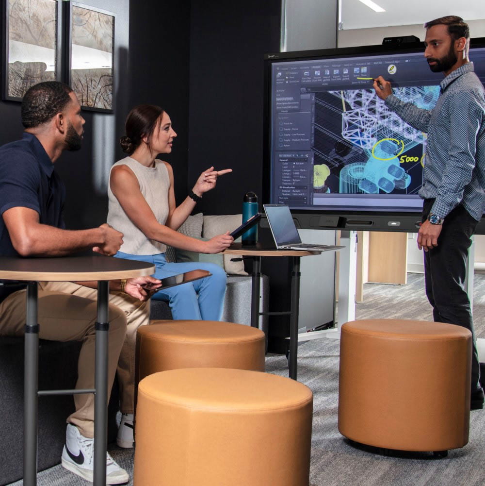 A team of three professionals collaborating around a SMART interactive display showing architectural design plans.