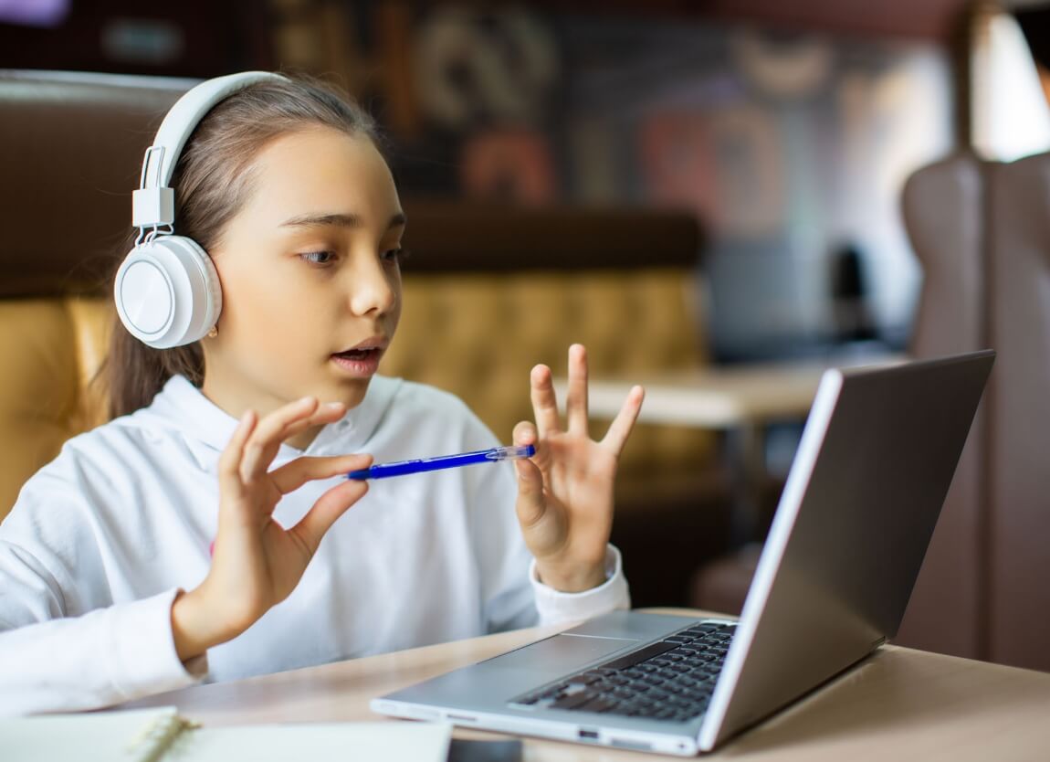Young student with headphones using a laptop, actively participating in an online learning session.