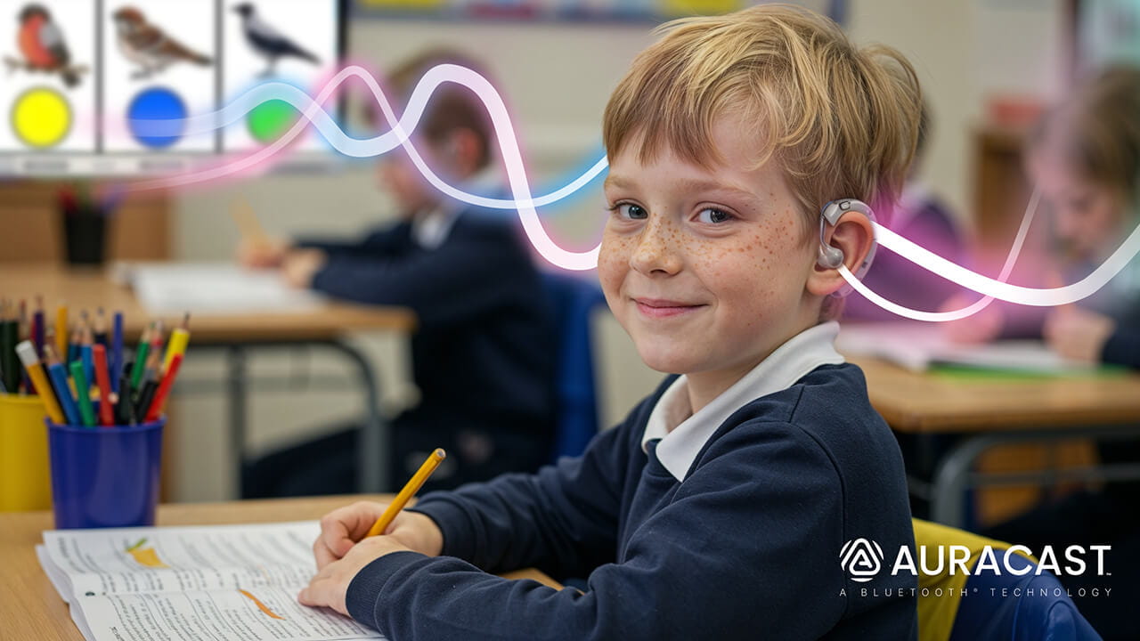 Smiling student in a classroom wearing a hearing aid