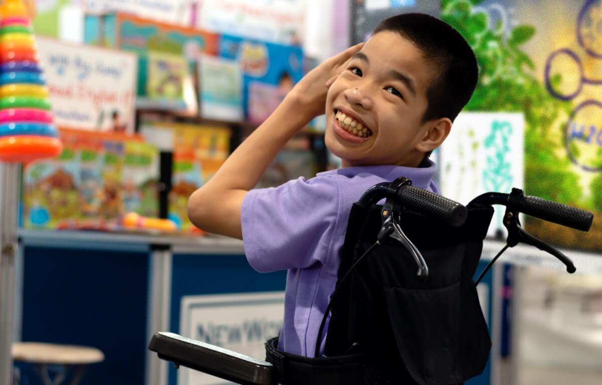 A happy student in a wheelchair interacting with educational content on a SMART Board, showcasing inclusive education technology.