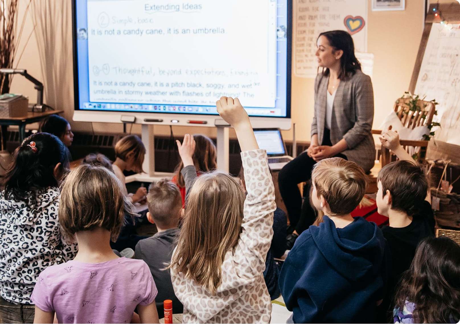 Young students participating in an interactive learning activity with a teacher at the front of the class.