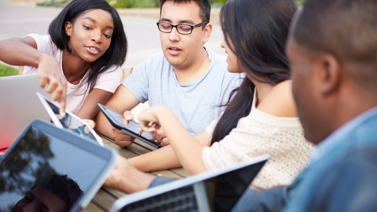 High school aged students collaborating over their individual tablets.