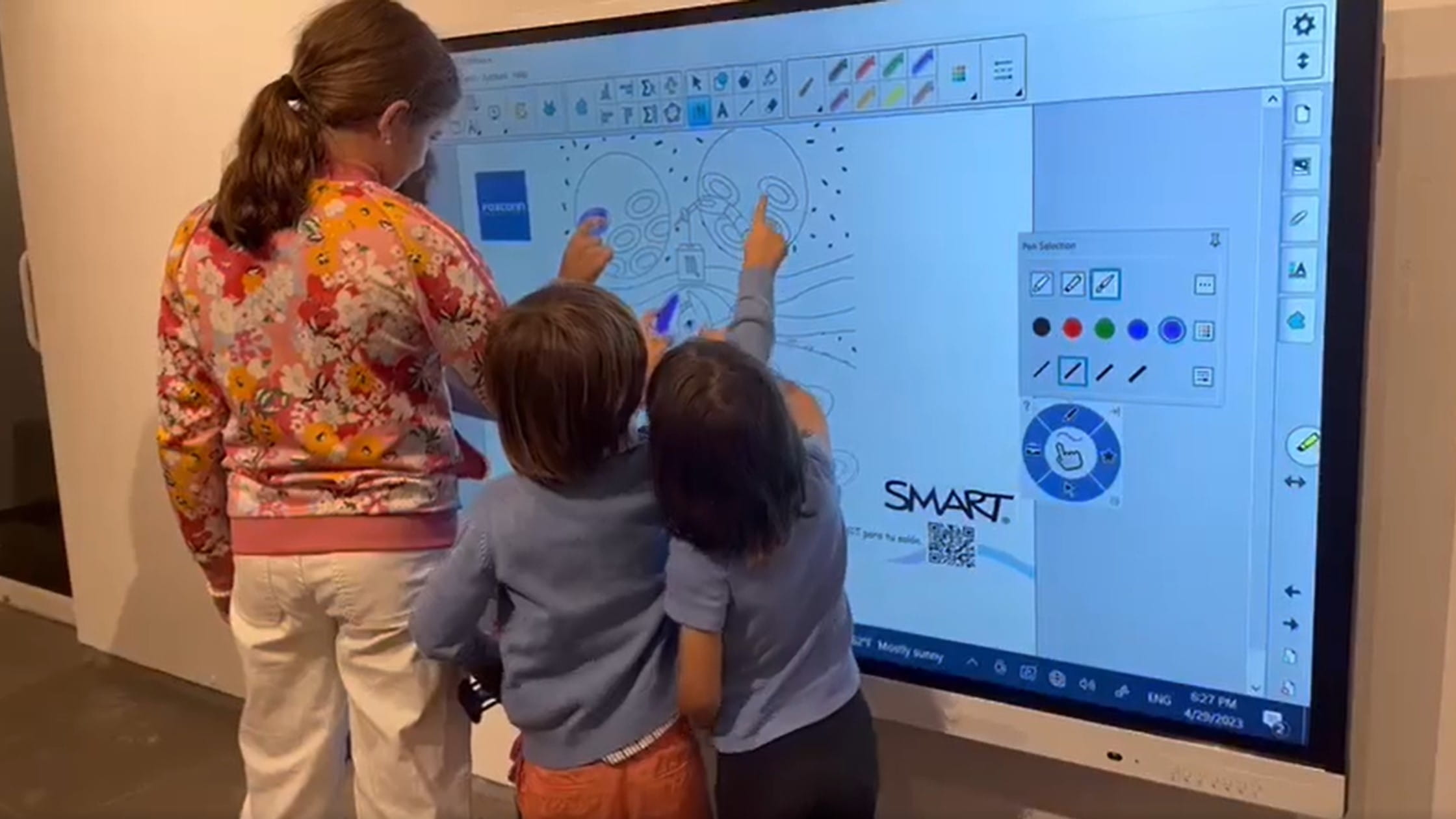 Un adulto y tres estudiantes interactúan con el tablero SMART  al mismo tiempo para crear una Mandala digital.