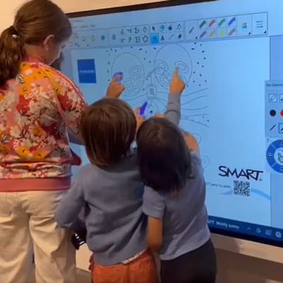 An adult and three students interacting with the SMART Board at once to create a digital Mandala.