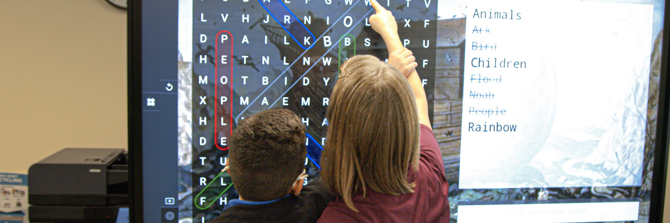 A teacher and student performing a crossword puzzel on a SMART board.