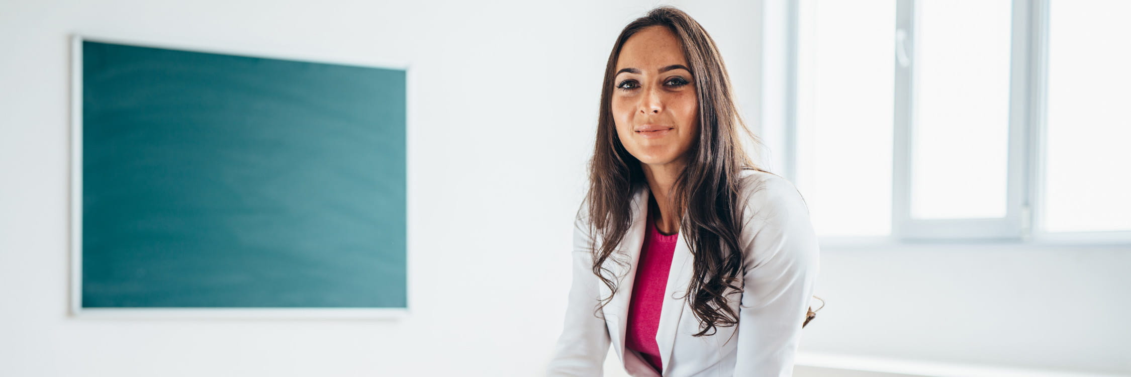 Female teacher in front of a green chalkboard.