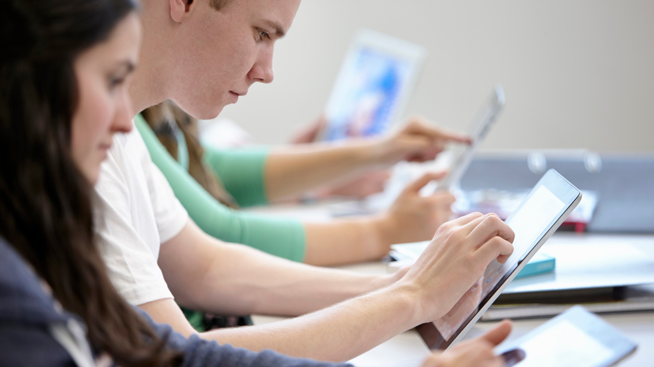 A middle-school aged student working independently on a tablet.