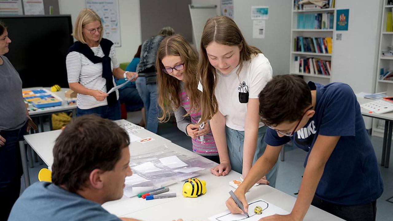 Group of students engaged in a hands-on learning activity, supported by teachers.