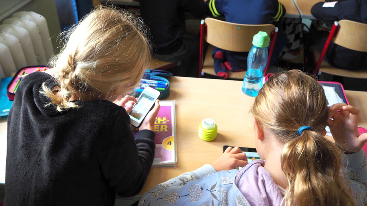 Students using smartphones for interactive learning during class.