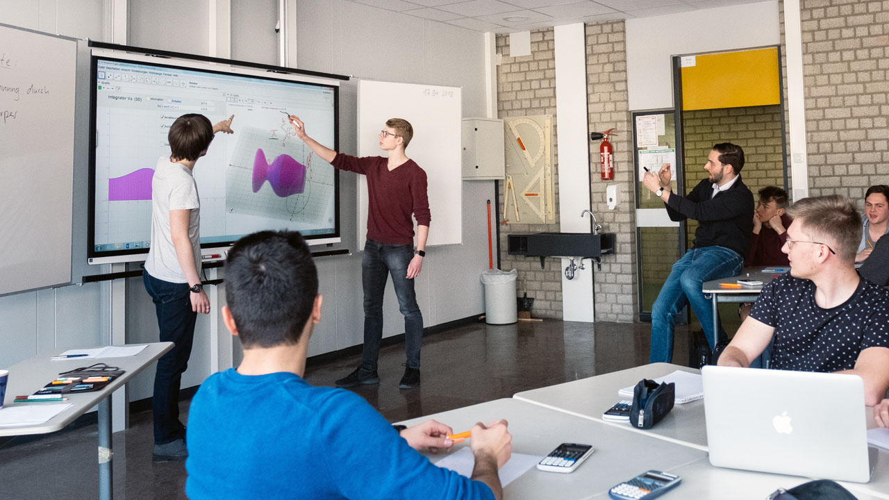Students presenting mathematical graphs and equations on a SMART Board in a classroom.
