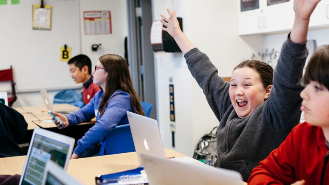 Student raising hands in joy amongst cheering classmates