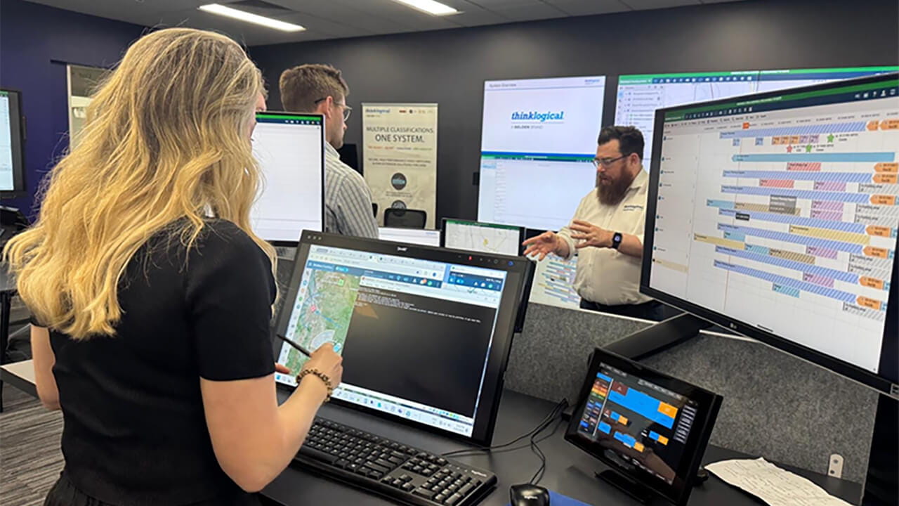 Team members using SMART Board Mini displays to review mapping, scheduling, and operational information in a command and control environment.