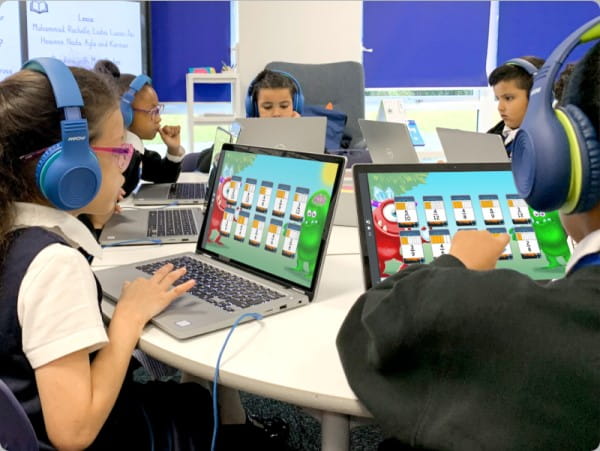 Students in a classroom attentively using computers to improve focus and attention on their tasks.