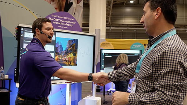 SMART employee shaking hands with a visitor at an event.