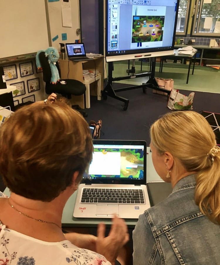 Two teachers conversing over a laptop