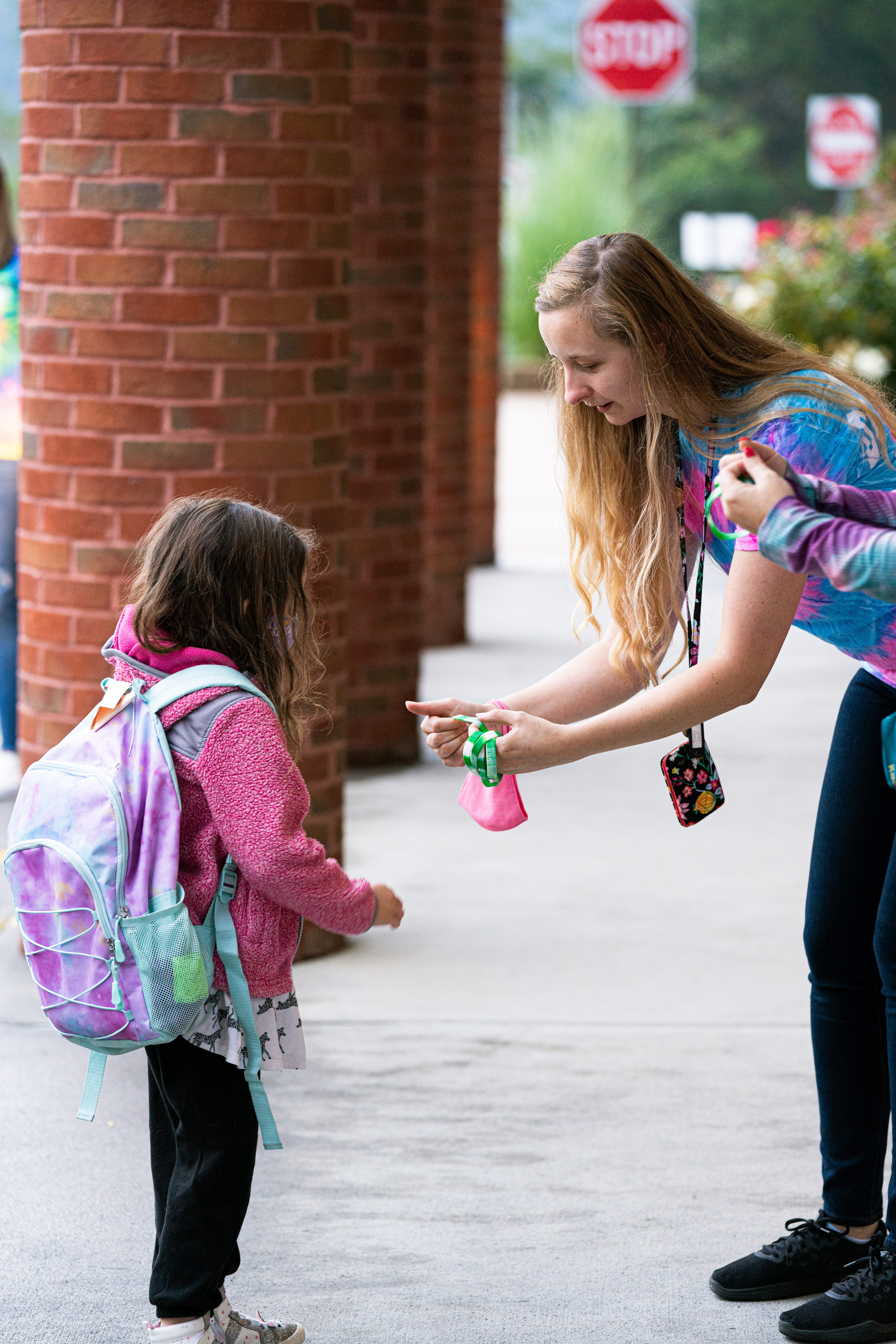 A student smiles at the camera while at her desk working on her student device.