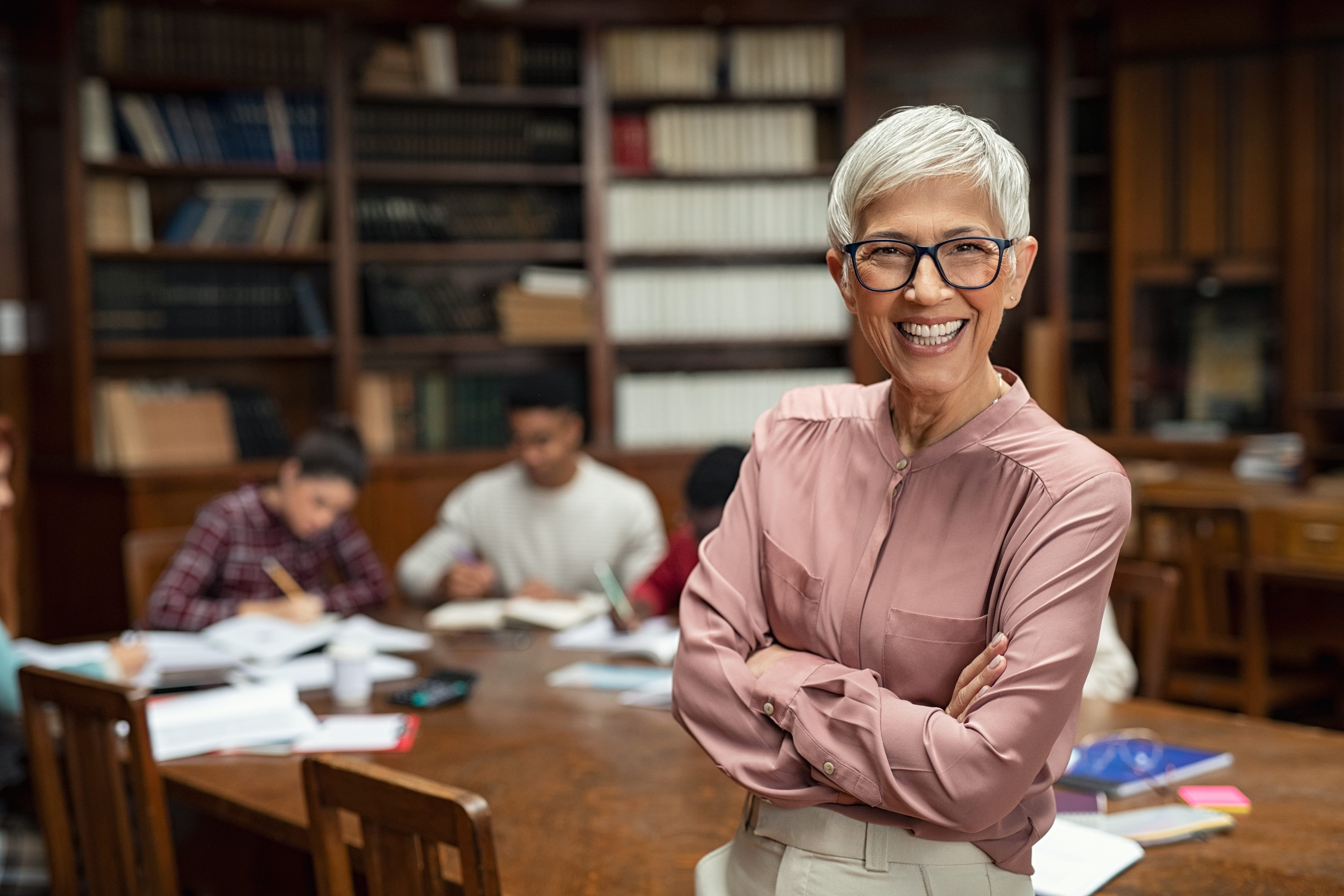 A happy librarian with students working independently in the background.