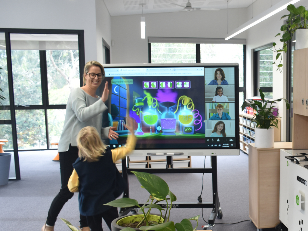 Teacher giving her student a high five in front of an interactive display