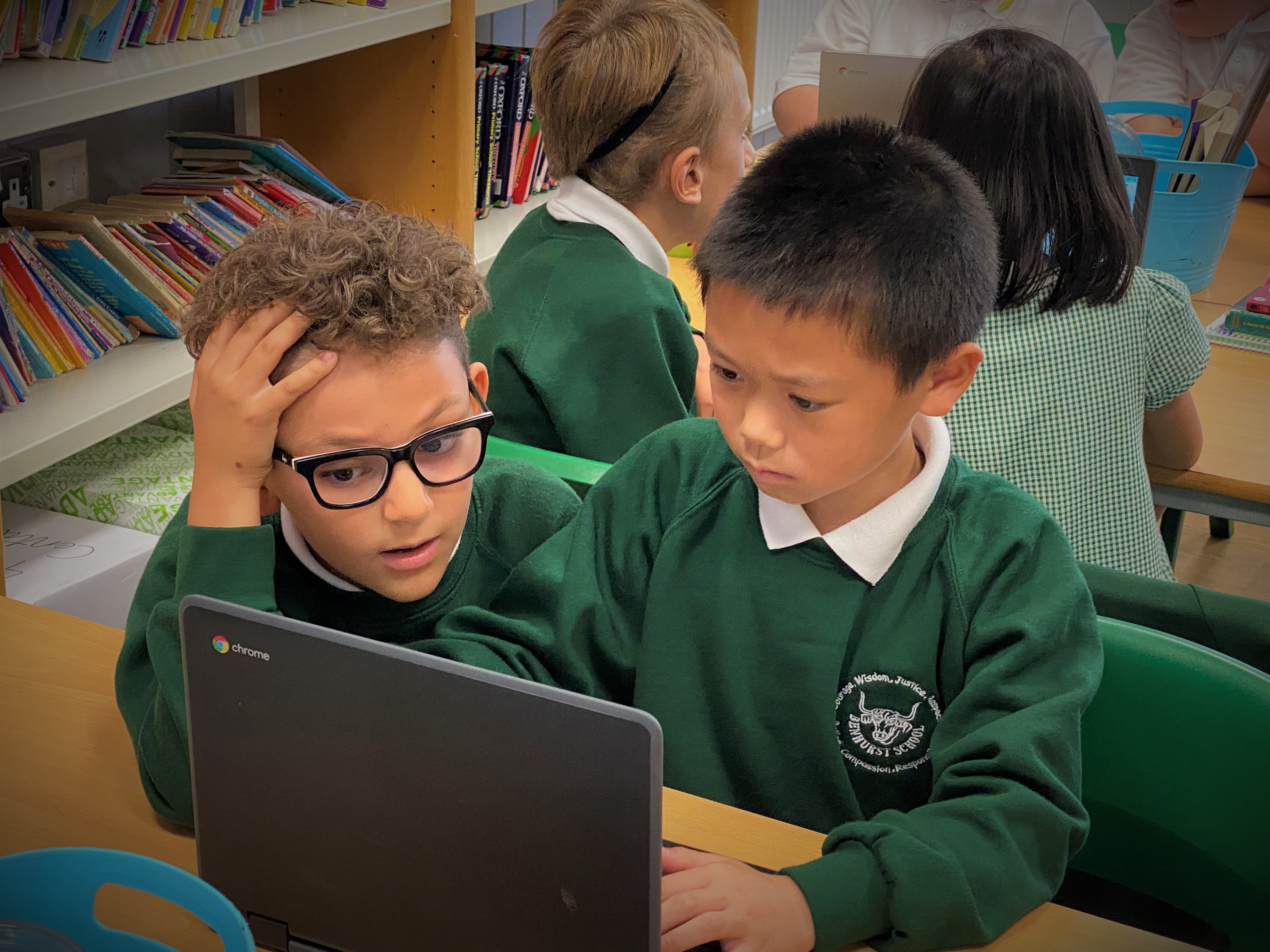 Two students collaborate on their devices during a lesson.