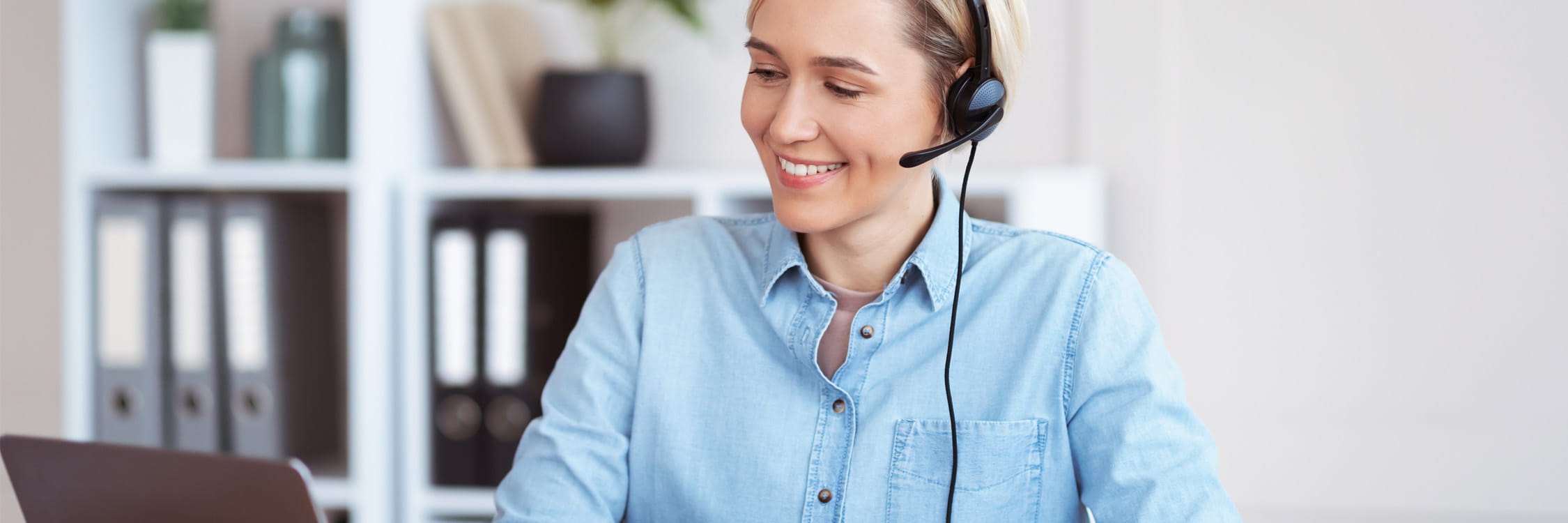 A woman with a headset on, engaged in online training.