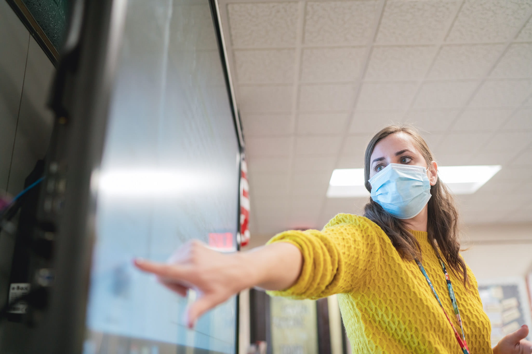 A teacher delivers a lesson at her SMART display with her mask on during the pandemic.