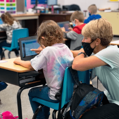 teacher helping student on student device