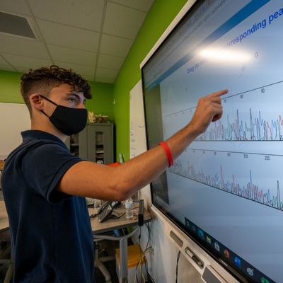 high school student using interactive display to plot data in classroom