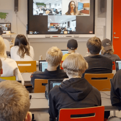 A class full of students communicating with classroom overseas using interactive display