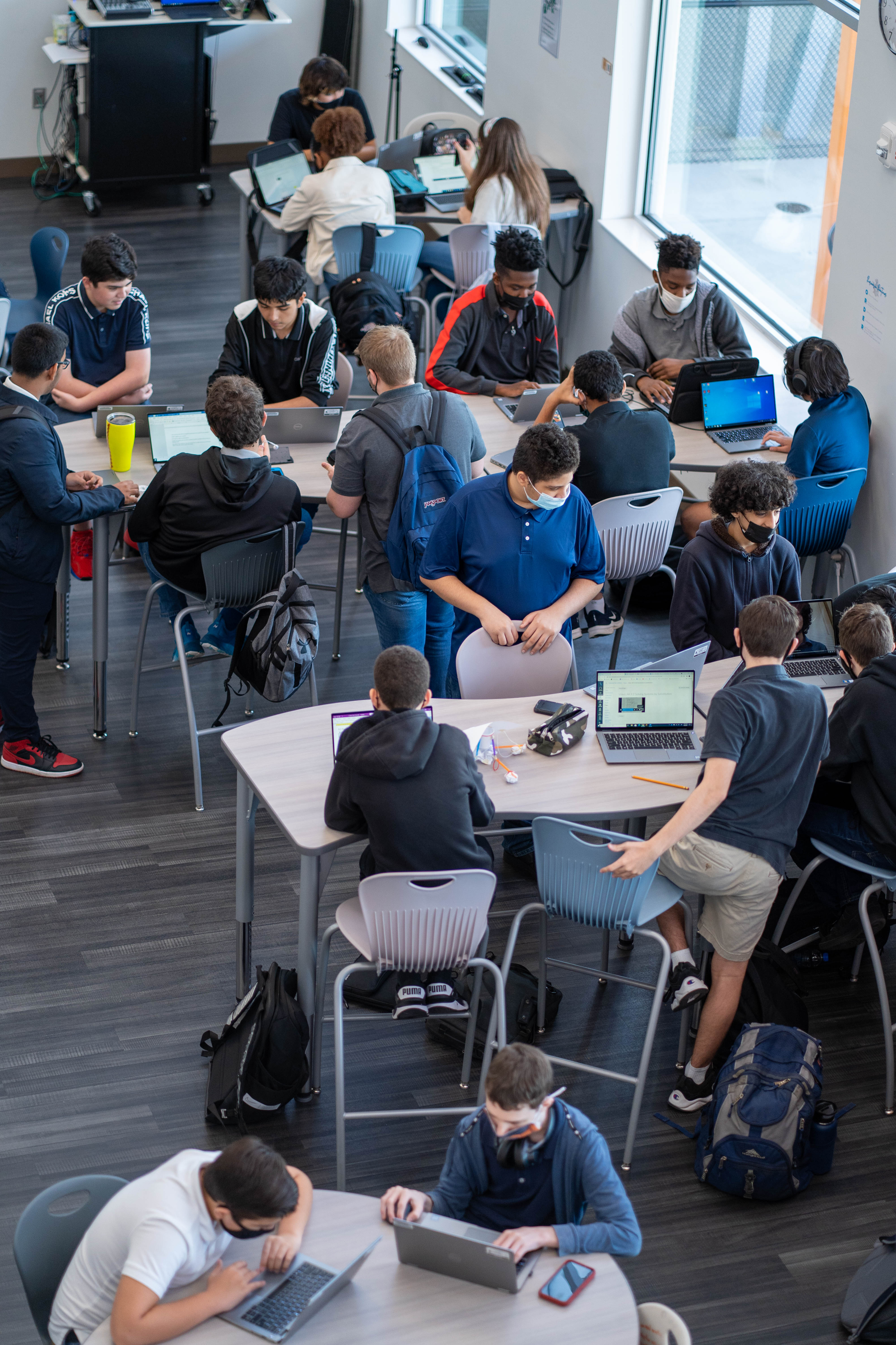 Students in a high school classroom collaborate using technology.Students in a high school classroom collaborate using technology.