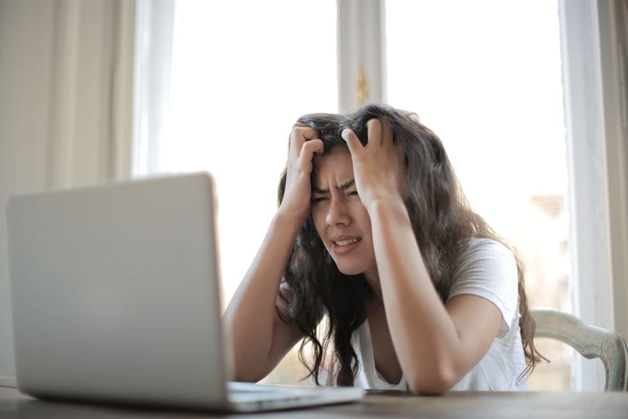 Young female visibly stressed in front of laptop