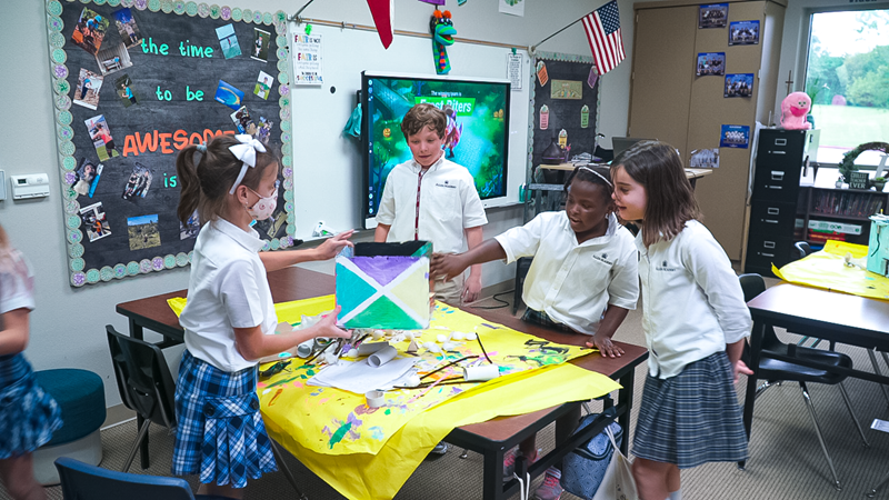 Students in a classroom collaborating on an art project with a SMART Board in the background.