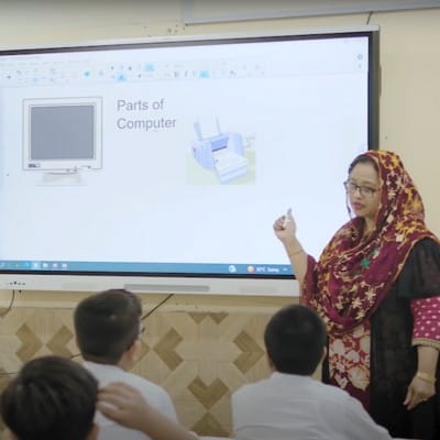 A student of Pakistan School Muscat engaging with a Geometry lesson on a SMART Board in front of his class and teacher.