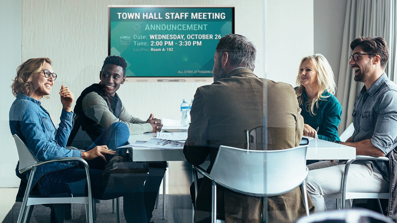 Digital signage displaying staff meeting information in a conference room.