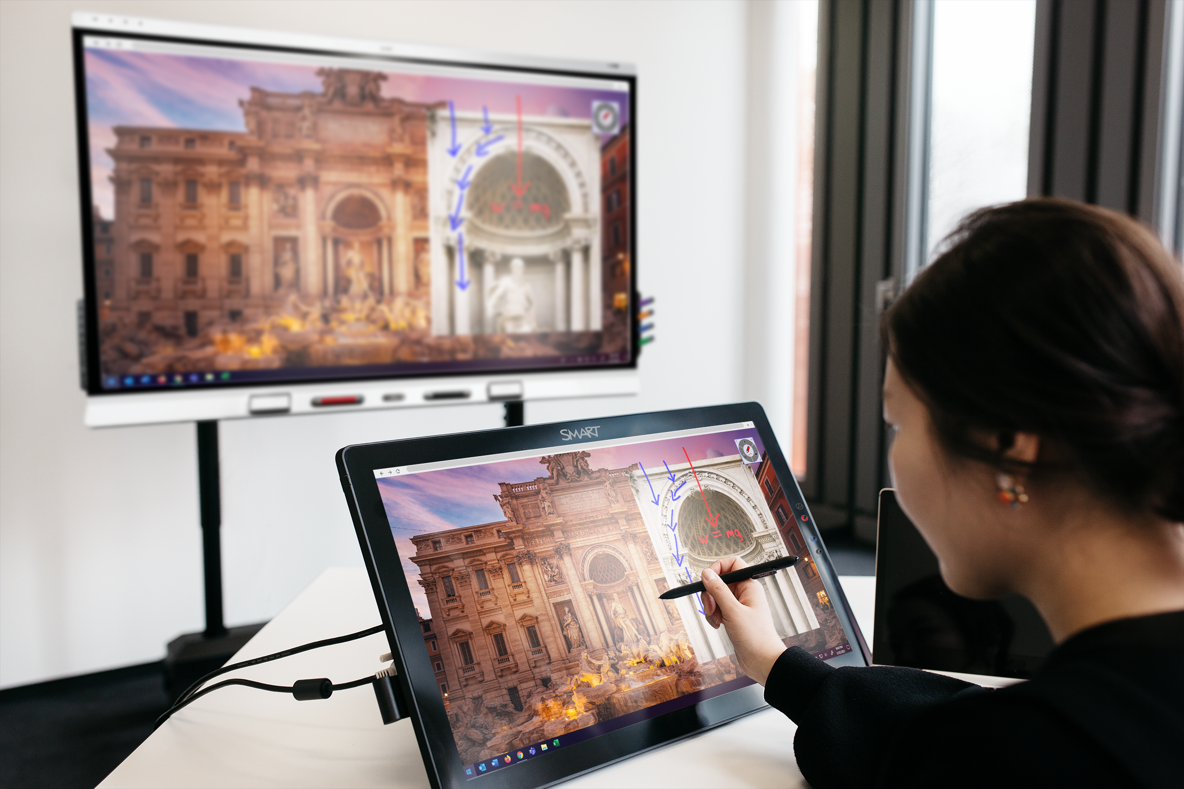 A teacher annotates on an image on her device. The annotation is then reflected on her interactive display.